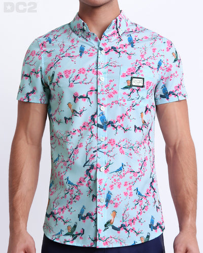 Male model wearing men’s CLOSE TO YOU men’s Summer button-down in a stylish exotic birds design in a light blue color with pink flowers. This high-quality shirt is by DC2, a men’s beachwear brand from Miami.
