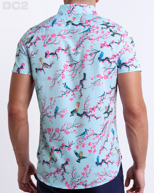 Male model wearing CLOSE TO YOU men’s sleeveless stretch shirt. Inspired by exotic birds on top of branches and pink flowers. This high-quality top by DC2, a men’s beachwear brand from Miami.