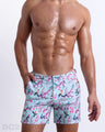 Male model wearing CLOSE TO YOU Tailored Shorts, premium swimwear with a stylish exotic birds design in a light blue color with pink flowers for men. These high-quality swimwear bottoms by DC2, a men’s beachwear brand from Miami.