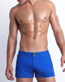 Frontal view of model wearing the CLUB BLUE men’s swim shorts featuring electric blue color by the Bang! brand of men's beachwear from Miami.