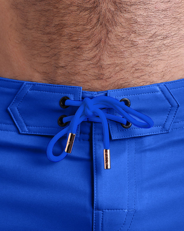 Close-up view of inseam and details of these shorts for men, with white cord and custom branded golden cord-ends, and matching custom eyelet trims in gold.