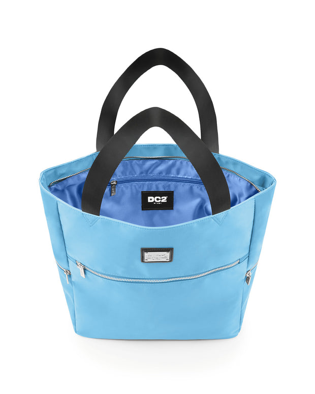 Top view of the COASTAL BLUE Poolside Tote Bag by DC2 Miami, showcasing the spacious interior with a visible DC2 Miami logo label. The bag features a blue color with sturdy black handles and multiple zippered compartments for secure storage.