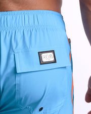 Close-up view of the COASTAL BLUE men’s Flex Boardshorts back pocket, showing custom branded silver metal logo.