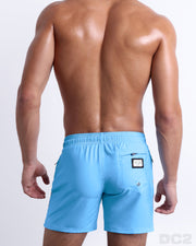 Back view of the COASTAL BLUE beach Resort Shorts in a solid baby blue color with orange and dark blue side stripes, complete the back pockets, made by DC2 a capsule brand by BANG! Clothes in Miami.