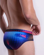 Back view of a model wearing CONFESSIONS ON A SAND FLR VOL 2 men’s beach brief in a multi color disco ball insapired by Madonna, Abba, and Studio 54 made by the Bang! Miami official brand of men's swimwear.