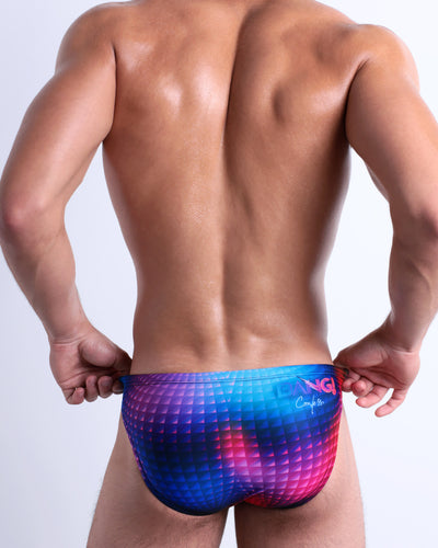 Back view of a model wearing CONFESSIONS ON A SAND FLR VOL 2 men’s beach mini-brief in a multi-color disco ball inspired by Madonna, Abba, and Studio 54 made by the Bang! Miami’s official brand of men's swimwear.