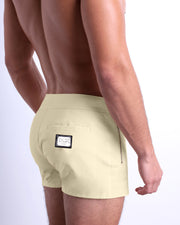 Side view of the CREAM FIELDS Summer Beach Shorts with dual zippered pockets for men featuring a solid light cream color is designed by BANG! Clothes in Miami.