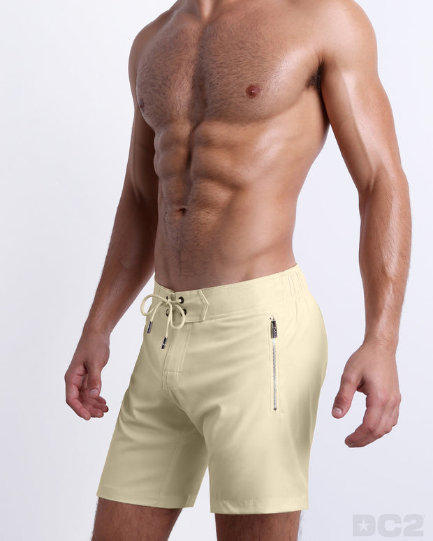 Side view of the CREAM FIELDS for men’s summer long boardshorts with dual zippered pockets. The shorts are vibrant in a solid pale yellow color made by DC2 a brand based in Miami.