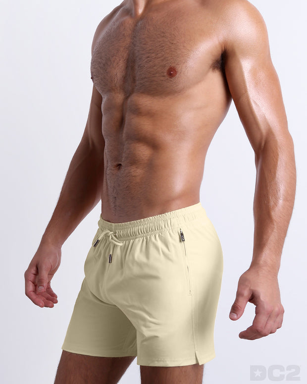 Side view of the CREAM FIELDS for men’s summer Resort Shorts with dual zippered pockets in a solid light pale yellow color designed by DC2 a brand based in Miami.