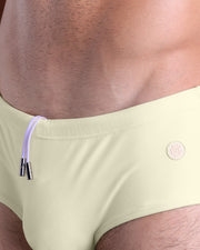 Close-up view of the CREAM FIELDS men’s drawstring briefs showing white cord with custom branded metallic silver cord ends, and matching custom eyelet trims in silver.