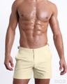 Male model wearing CREAM FIELDS swimming Tailored Shorts, in a light pale yellow color for men. These premium quality swimwear bottoms are DC2 by BANG! Clothes, a men’s beachwear brand from Miami.