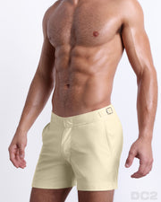 Side view of the CREAM FIELDS swimsuit Tailored Shorts with dual pockets and adjustable side buckles for men featuring a light pale yellow color is designed by BANG! Clothes in Miami.