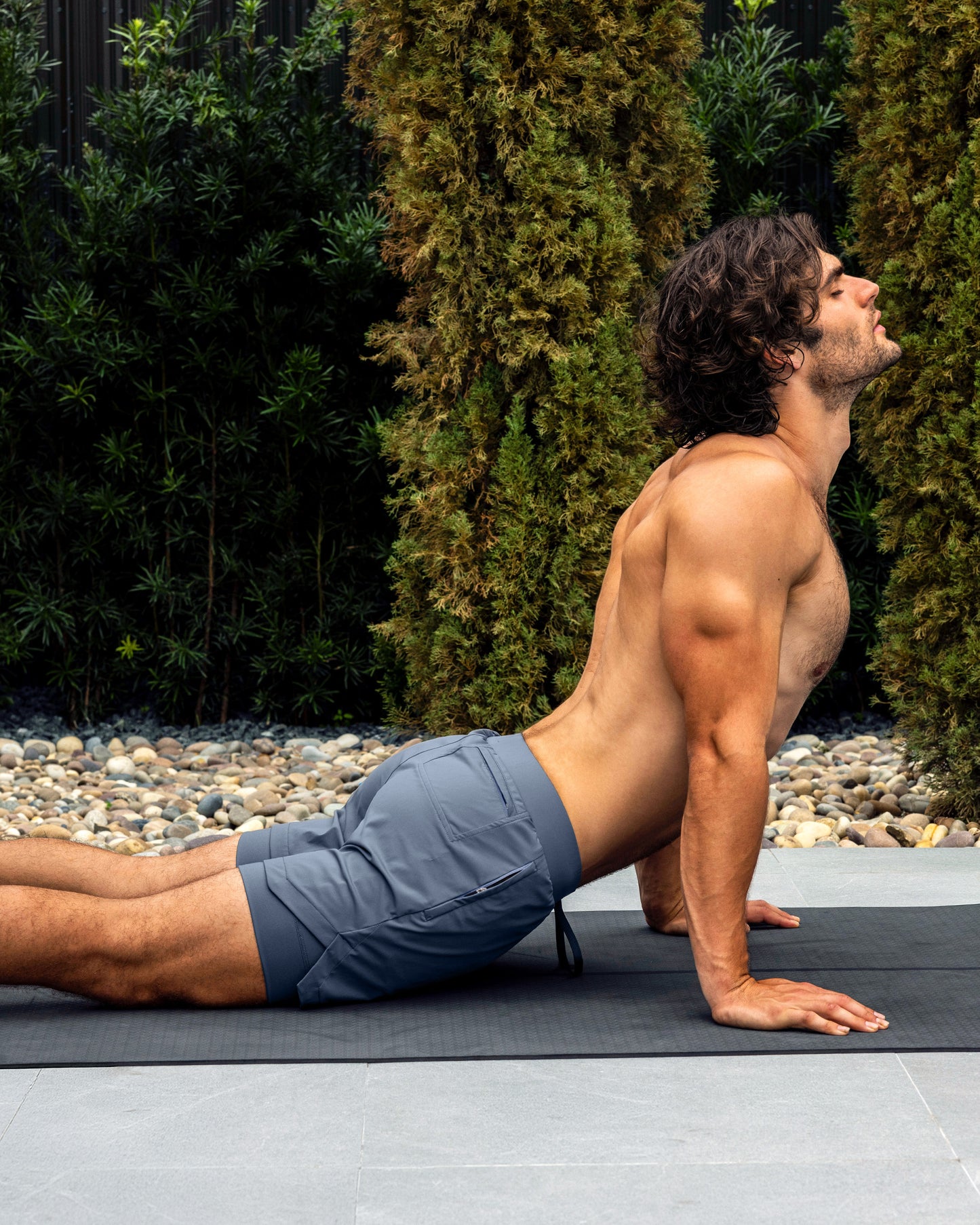 BANG Miami Cross Train Blue Endurance 2-in-1 Gym Shorts — model wearing blue men’s training shorts on a yoga mat outdoors.