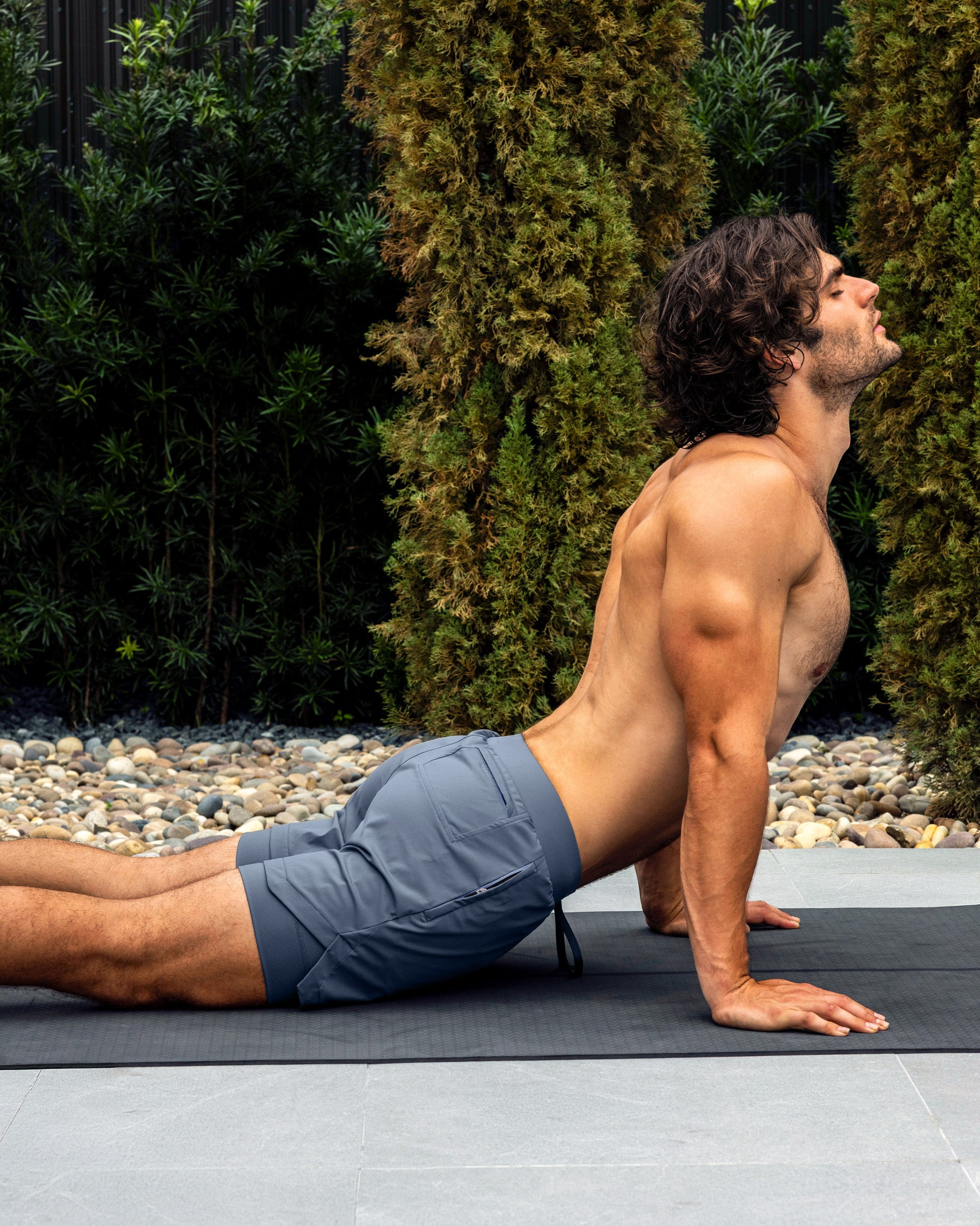 BANG Miami Cross Train Blue Endurance 2-in-1 Gym Shorts — model wearing blue men’s training shorts on a yoga mat outdoors.