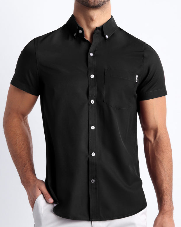 Front view of a sexy male model wearing DARK KNIGHT mens short-sleeve stretch shirt in a solid black color by the Bang! brand of men&