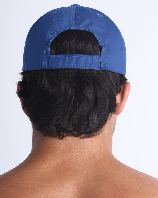 The DENIM BLUE Chillax Cap, modeled here, is in blue. Its adjustable velcro strap at the back ensures a perfect fit for any head size.