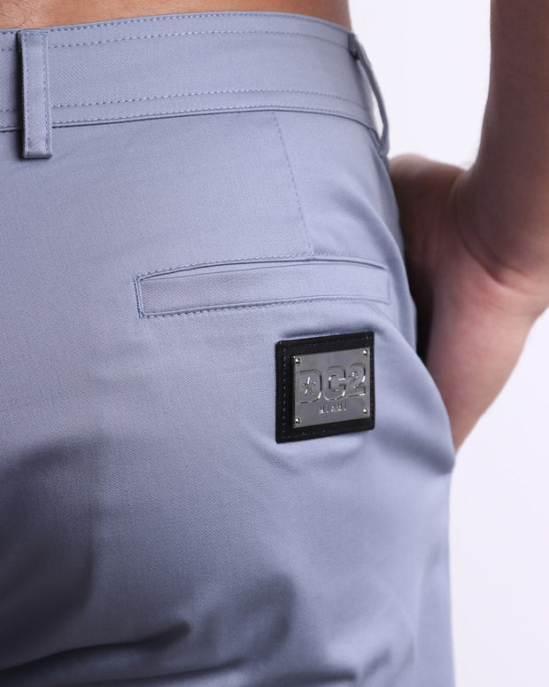 Close up view of cotton fabric chino street shorts back pocket with custom engraved DC2 silver logo plaque.