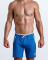 Frontal view of male model wearing the ELECTRO BLUE athletic crossfit gym shorts in a solid blue color by the Bang! brand of men's beachwear from Miami.