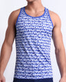 Male model wearing ESCAPADE (BLUE/WHITE) beach Tank Top, premium swimwear with a stylish blue and white graphic monogram print for men. This high-quality Summer top by BANG! Clothes, a men’s beachwear brand from Miami.