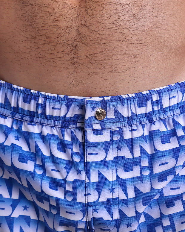 Close-up view of the ESCAPADE (BLUE/WHITE) men’s Mini shorts, showing custom branded metal button in gold by Bang!