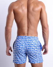 Back view of a male model wearing men’s ESCAPADE (BLUE/WHITE) beach Resort Shorts swimsuit in a blue and white monogram design made by BANG! Clothes in Miami.
