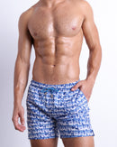 Male model wearing ESCAPADE (BLUE/WHITE), premium swimwear with a stylish blue and white graphic monogram print for men. These high-quality swimwear bottoms by BANG! Clothes, a men’s beachwear brand from Miami.