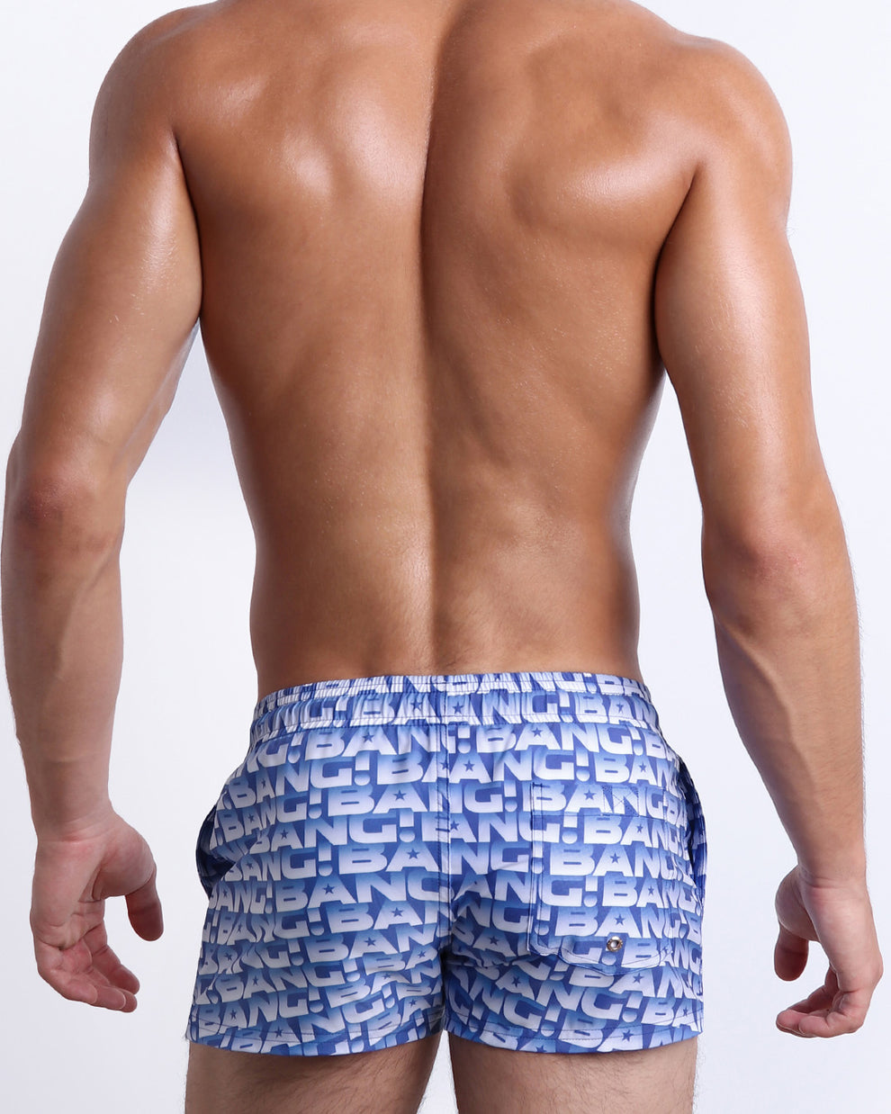 Back view of a male model wearing men’s ESCAPADE (BLUE/WHITE) beach Show Shorts swimsuit in a blue and white monogram design made by BANG! Clothes in Miami.