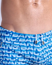 Close-up view of the ESCAPADE (BLUE/WHITE) men’s drawstring briefs showing white cord with custom branded golden cord ends, and matching custom eyelet trims in gold.