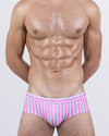 Model wearing FAST LINES (CHILL PINK) men’s swim briefs in bold candy pink and white vertical stripes. This updated classic fit channels retro beach club vibes with a low-rise cut and athletic, body-sculpting design that pops poolside or seaside.