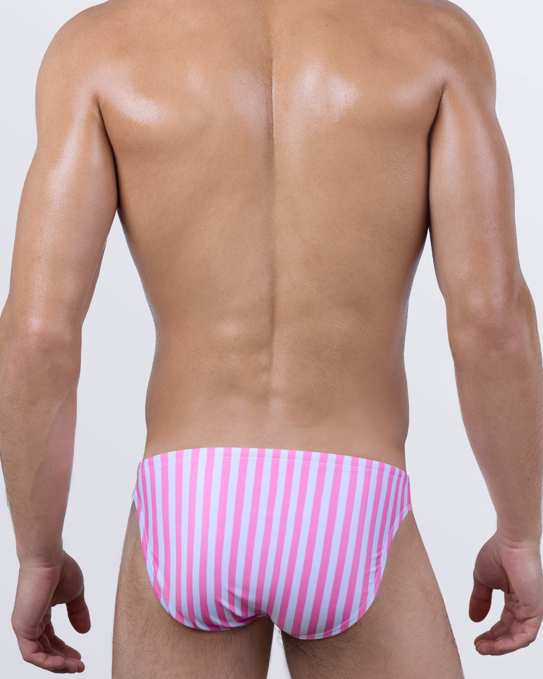 Back view of FAST LINES (CHILL PINK) men’s swim mini briefs, showcasing the vertical striped pattern in pastel pink and white tones. Edgy men’s resort swimwear designed to contour and flaunt in all the right ways.