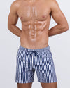 Frontal view of a male model wearing the FAST LINES (NAVY BLUE) Resort Shorts for men by DC2 Miami. These above-the-knee swim shorts feature a classic navy blue and white striped pattern, an elastic waistband with an adjustable drawstring, and a relaxed fit, perfect for poolside lounging, tropical vacations, and summer getaways.