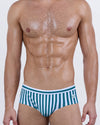 Model wearing FAST LINES (Pacific Green) men’s swim briefs with vertical white and emerald green stripes. The sleek silhouette and supportive structure give a modern twist to the timeless swim brief cut.