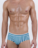 Model wearing FAST LINES (Pacific Green) men’s swim briefs with vertical white and emerald green stripes. The sleek silhouette and supportive structure give a modern twist to the timeless swim brief cut.