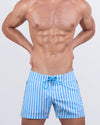 A male model wearing the FAST LINES (SKY BLUE) - Flex Shorts by DC2 Miami. These premium shorts feature a vibrant sky blue and white vertical stripe pattern, a lace-up front, and water-resistant metallic zippers.
