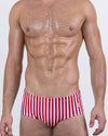 Model wearing FAST LINES (RAPID RED) men’s swim sunga in bold red with crisp white vertical stripes. A striking Brazilian cut designed for confident summer energy with a snug, mid-rise silhouette.