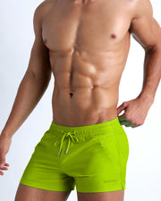 Side view of men’s shorter leg length shorts with dual pockets for men in a light green solid color made by Miami based BANG! brand of men's beachwear.