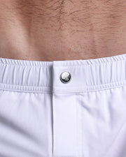 Close-up view of the FORZA WHITE men’s swimwear, showing custom branded silver metal logo.