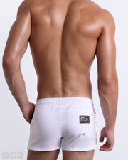 Back view of male model wearing men’s FORZA WHITE beach Poolside Shorts swimsuits in a solid white color with green and red side stripes, complete the back zippered pocket, made by DC2 a capsule brand by BANG! Clothes in Miami.