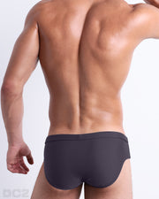 Back view of male model wearing the GOTHAM GREY beach briefs for men by BANG! Miami in a solid smoke grey color.