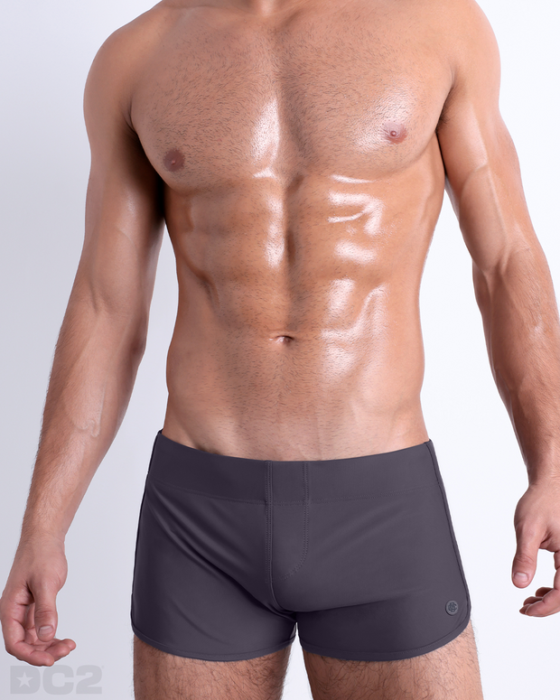 Front view of model wearing the GOTHAM GREY men’s swimming bottoms in a solid dark grey color by DC2, a men&