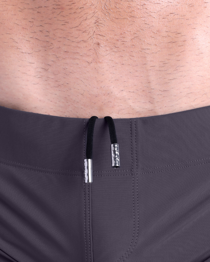 Close-up view of men’s summer beach shorts by DC2 clothing brand, showing black cord with custom branded metallic silver cord ends.