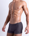 DC2 GOTHAM GREY Swim Trunks — model wearing square-cut skin-hugging swim trunks in sleek grey with a subtle shine finish.