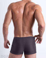 Back view of a male model wearing the GOTHAM GREY men’s swim trunks by BANG! Miami in a solid smoke grey color.