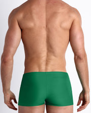 Back view of a male model wearing the GREEN RUSH men’s swim trunks in solid forest green color made with Italian-made Vita By Carvico Econyl Nylon by the Bang! Clothes brand of men's beachwear from Miami.