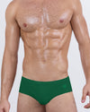 DC2 Spring/Summer 2025 collection — model wearing GREEN RUSH swim briefs, featuring a clean low-rise silhouette in a bold, energizing green tone.