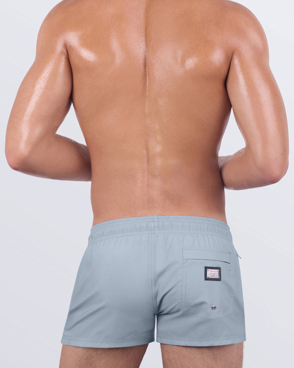 Back view of GREY ANATOMY men’s poolside shorts featuring an elastic waistband, rear zip pocket, and subtle metal branding patch in a modern neutral color.