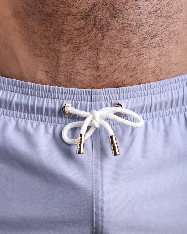 Close-up view of the GRAY ANATOMY men’s summer shorts, showing white cord with custom branded golden cord ends, and matching custom eyelet trims in gold.