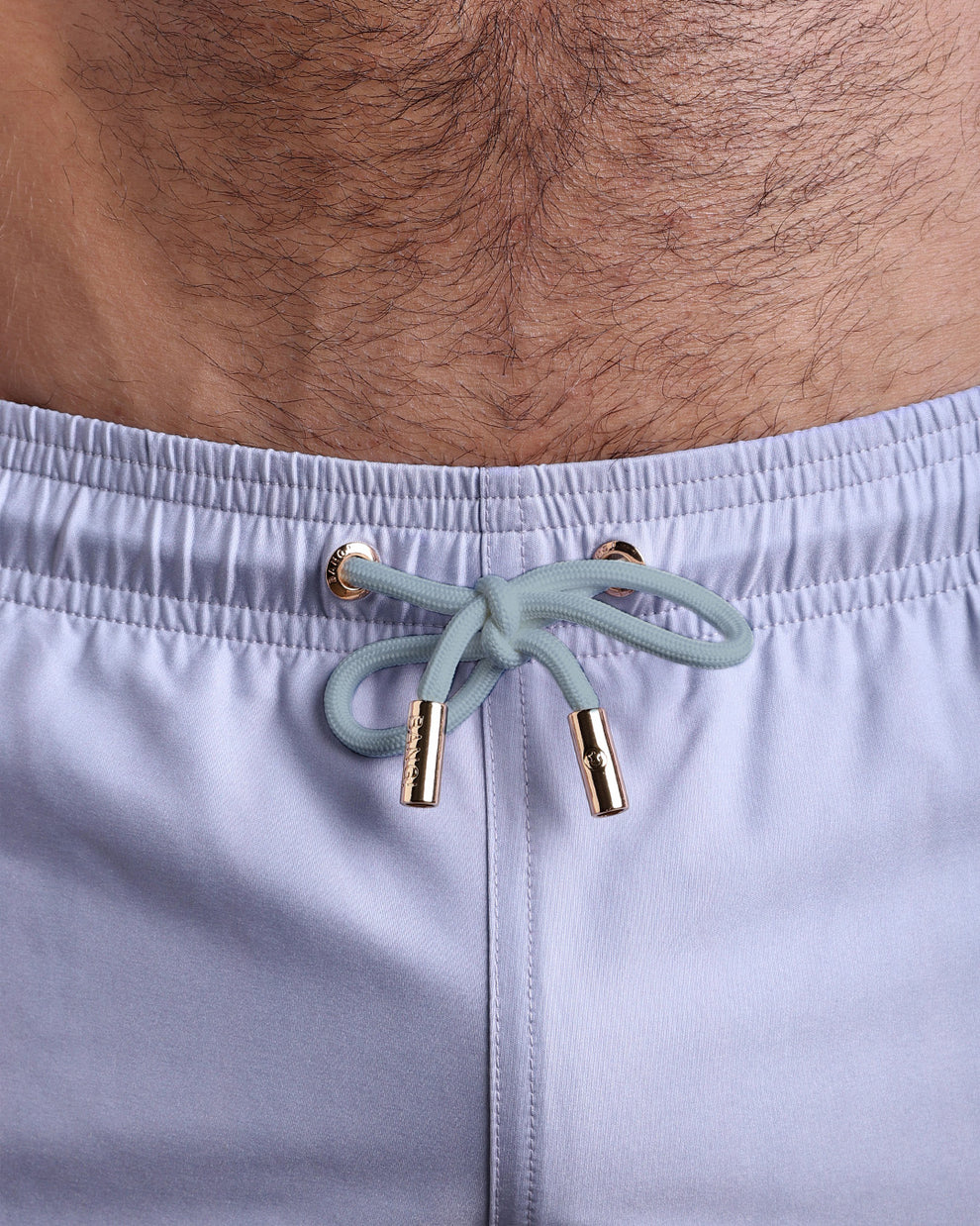 Close-up view of the GRAY ANATOMY men’s summer shorts, showing white cord with custom branded golden cord ends, and matching custom eyelet trims in gold.