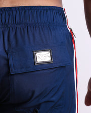 Close-up view of the IMPERIAL BLUE men’s Flex Shorts back pocket, showing custom branded silver metal logo.