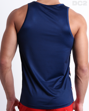 Male model wearing men’s IMPERIAL BLUE men’s Summer Tank Top in dark blue color with stylish white and red colored stripes. This high-quality shirt is by DC2, a men’s beachwear brand from Miami.